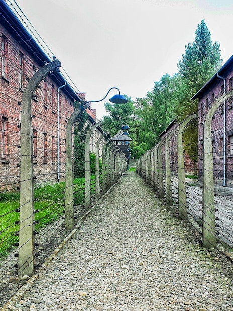 Barbed wire fences and brick buildings at Auschwitz-Birkenau, Poland.