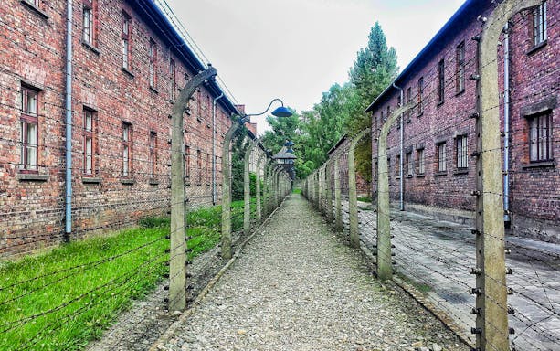 Barbed wire fences and brick buildings at Auschwitz-Birkenau, Poland.