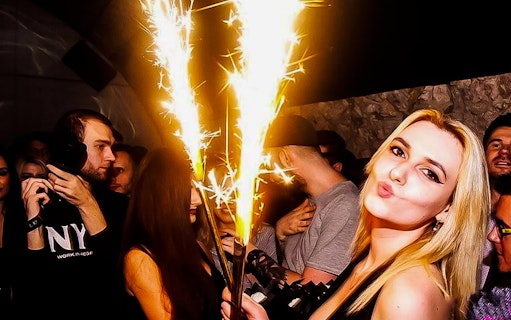 Krakow pub crawl with people celebrating and holding sparklers.