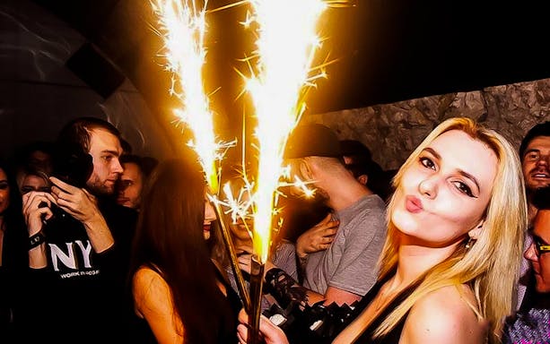 Krakow pub crawl with people celebrating and holding sparklers.