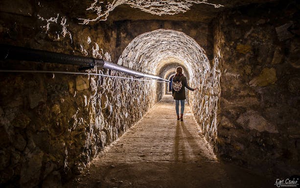 Person walking through Buda Castle Cave tunnel on English guided tour.