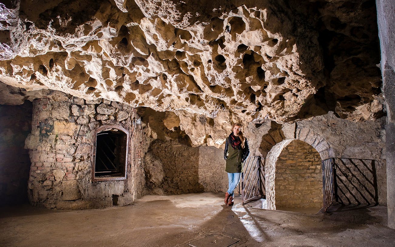 Buda Castle Cave interior with visitor on English guided tour.