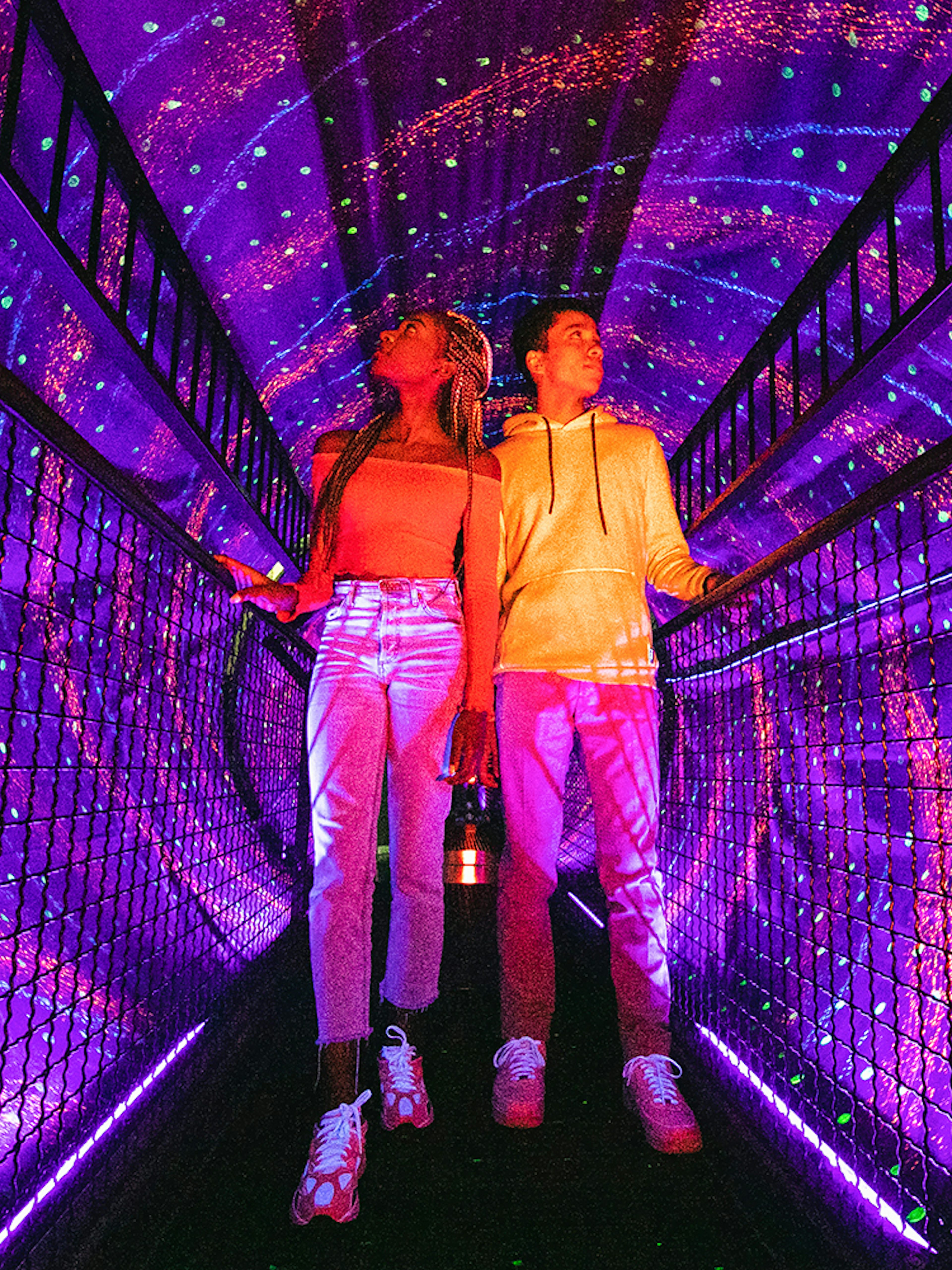 Visitors exploring a vibrant light tunnel at Illuseum Berlin.