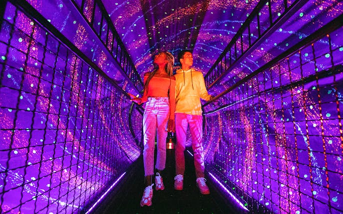 Visitors exploring a vibrant light tunnel at Illuseum Berlin.