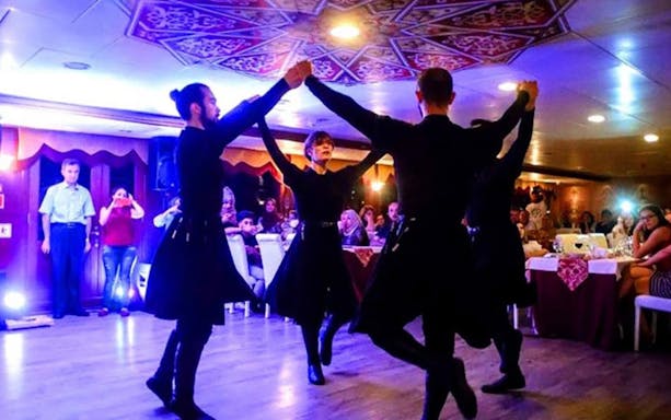 Dancers performing traditional dance on Bosphorus dinner cruise with audience watching.