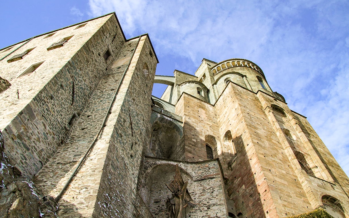 Sacra di San Michele stone facade under blue sky, part of Torino half-day medieval tour.