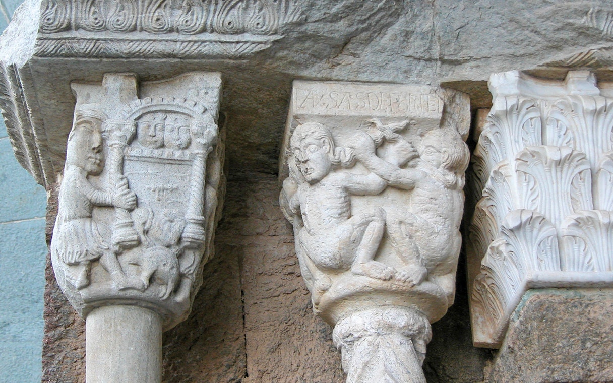 Stone carvings at Sacra di San Michele, featuring medieval figures and intricate designs.