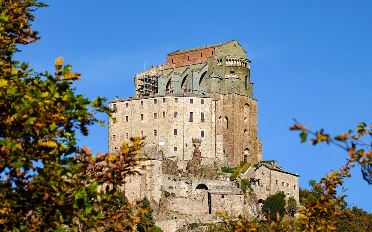 Sacra di San Michele abbey on a hilltop near Torino, surrounded by autumn foliage.