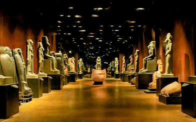 Ancient Egyptian statues in a dimly lit gallery at the Egyptian Museum of Turin.