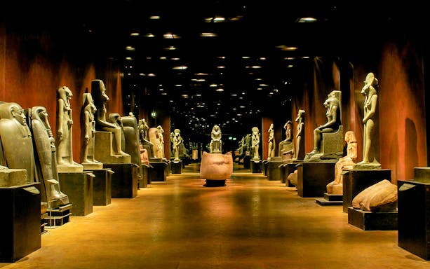 Ancient Egyptian statues in a dimly lit gallery at the Egyptian Museum of Turin.