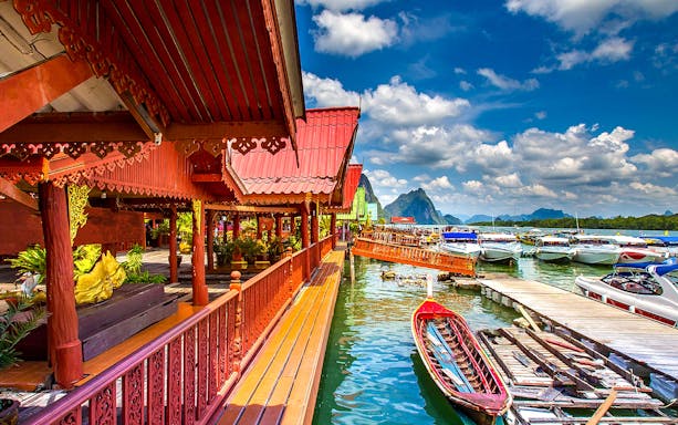 Traditional Thai architecture by the water with boats, James Bond Island tour.
