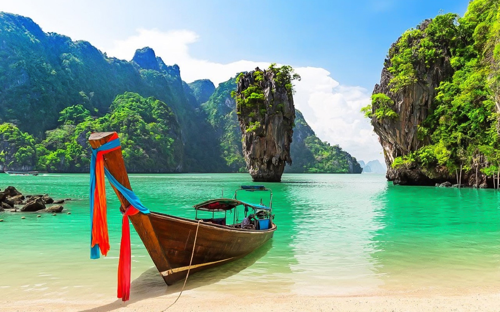 Longtail boat on the shore with James Bond Island in the background, Phang Nga Bay, Thailand.
