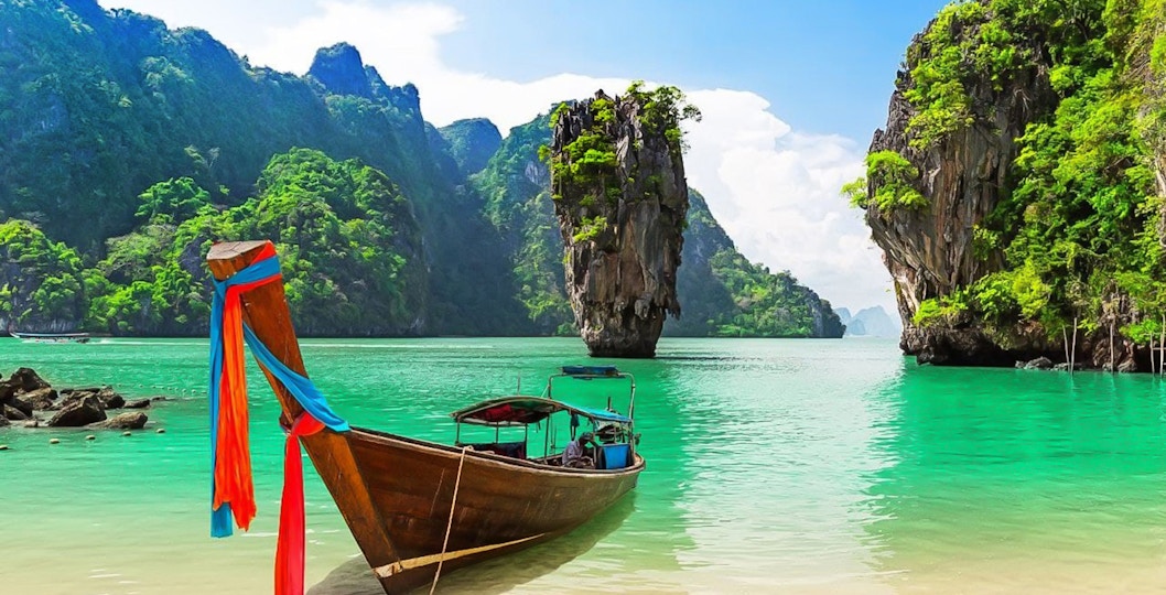 Longtail boat on the shore with James Bond Island in the background, Phang Nga Bay, Thailand.