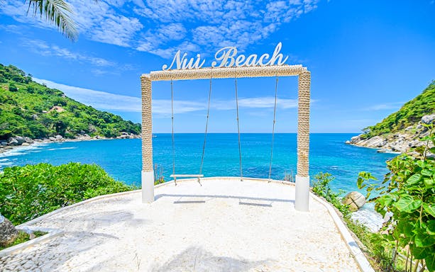 Swing overlooking the ocean at Nui Beach, Phuket, surrounded by lush greenery.