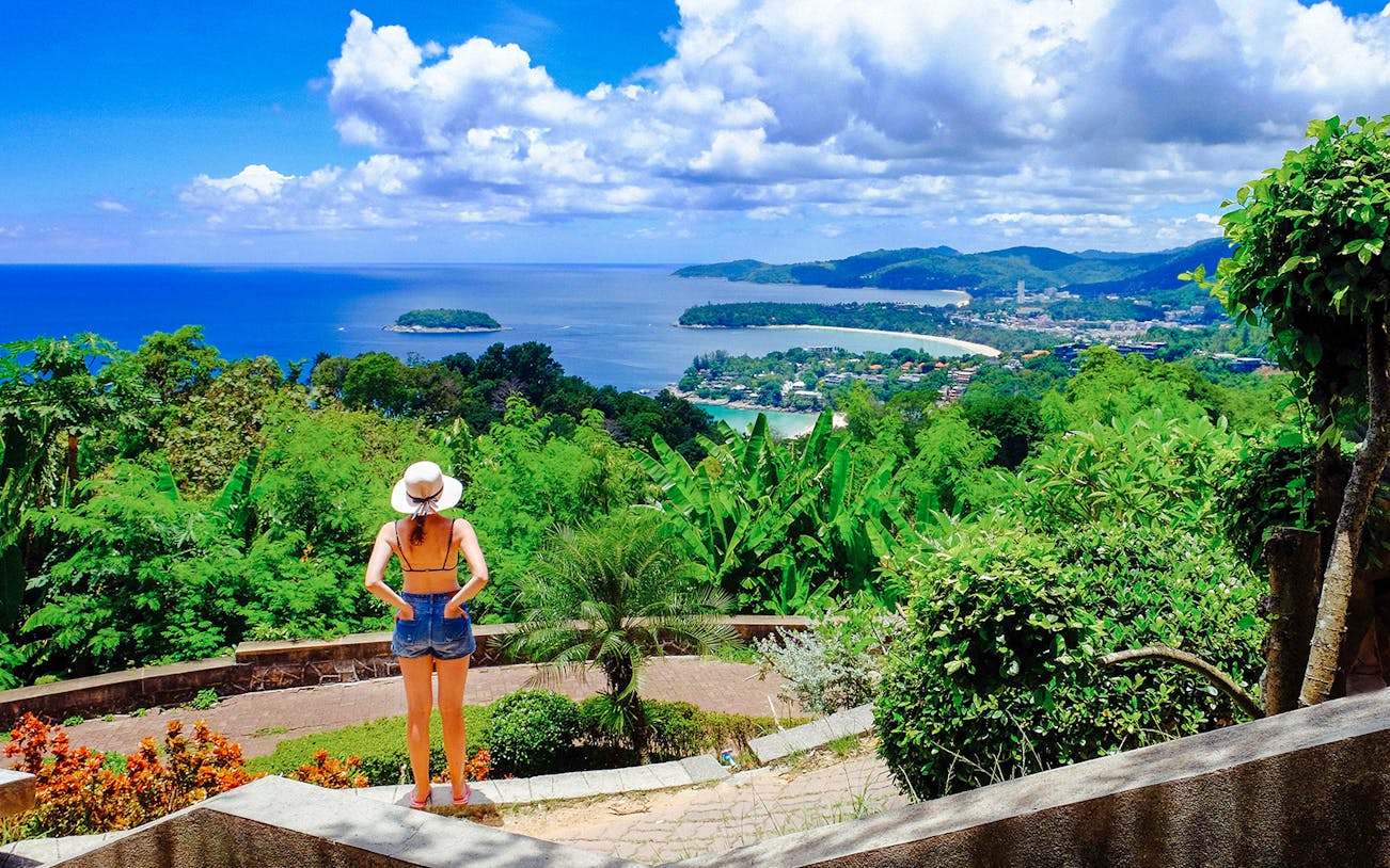 Woman overlooking lush greenery and ocean view in Phuket, Thailand.