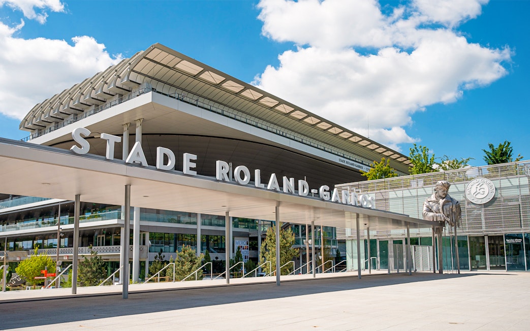 Roland-Garros Stadium entrance with modern architecture and statue, Paris.