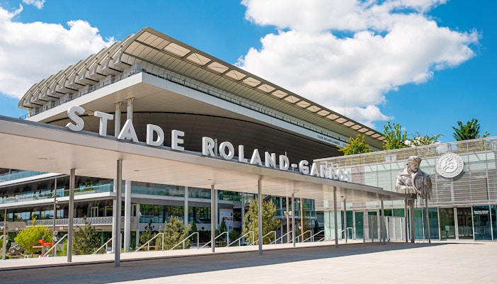 Roland-Garros Stadium entrance with modern architecture and statue, Paris.