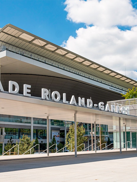 Roland-Garros Stadium entrance with modern architecture and statue, Paris.