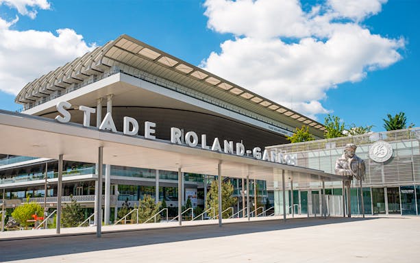 Roland-Garros Stadium entrance with modern architecture and statue, Paris.