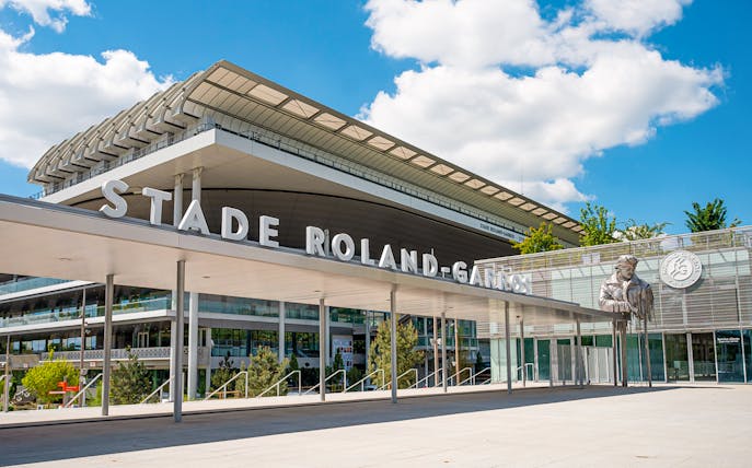 Roland-Garros Stadium entrance with modern architecture and statue, Paris.