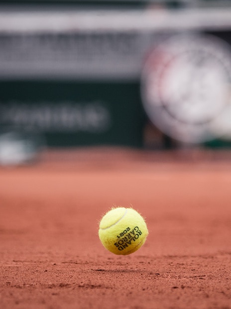 Tennis ball on clay court at Roland Garros Stadium.