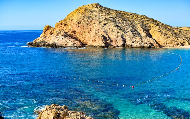 Rocky coastline and clear blue waters at Two Bays, Cabo, ideal for glass bottom kayaking and snorkeling.