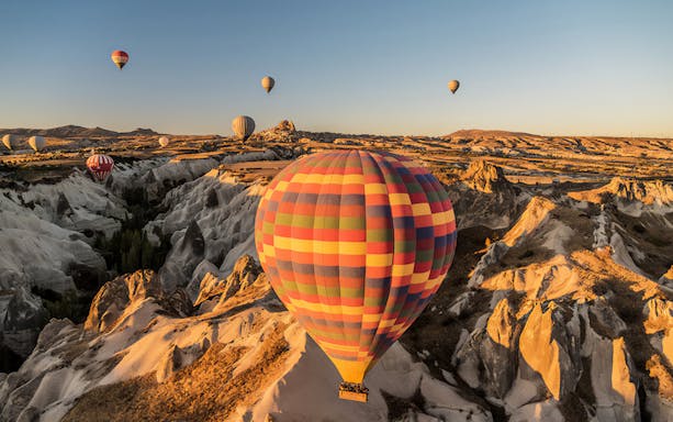 Hot air balloons over Cappadocia's unique rock formations at sunrise.