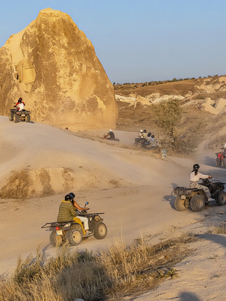 ATVs driving through Cappadocia's rocky landscape during a guided tour.