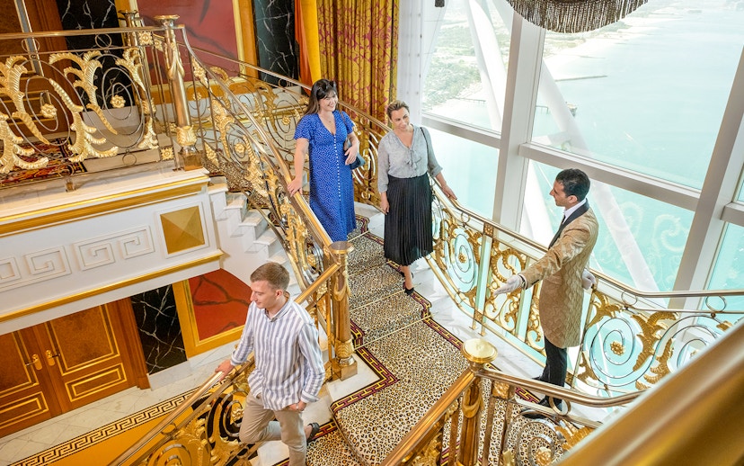 Guests exploring ornate staircase during guided tour inside Burj Al Arab, Dubai.