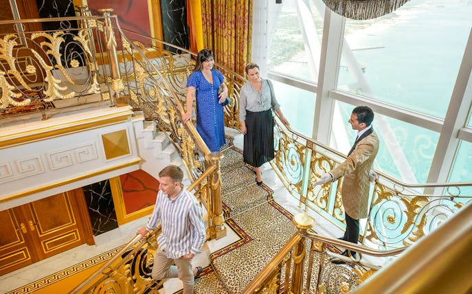 Guests exploring ornate staircase during guided tour inside Burj Al Arab, Dubai.