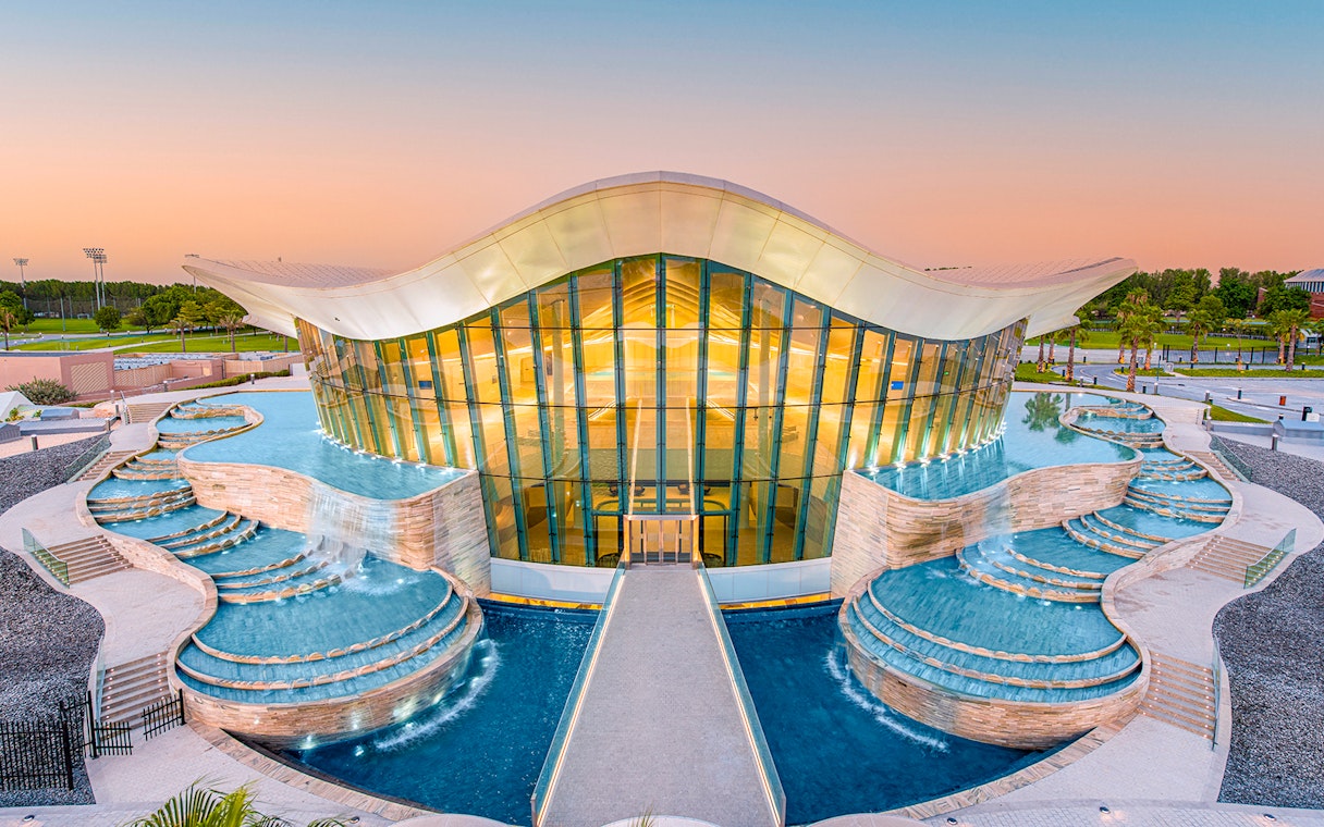Deep Dive Dubai building with cascading pools at sunset.