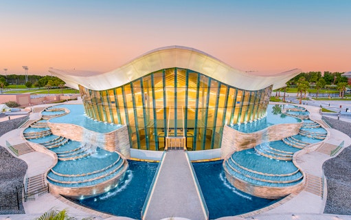 Deep Dive Dubai building with cascading pools at sunset.