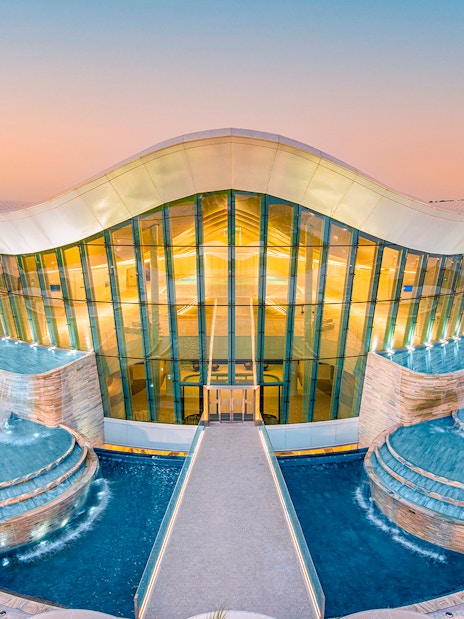Deep Dive Dubai building with cascading pools at sunset.
