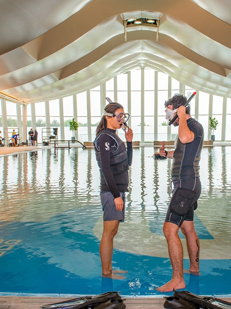 Snorkelers preparing in Deep Dive Dubai's indoor pool.