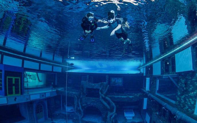 Snorkelers exploring underwater cityscape at Deep Dive Dubai.