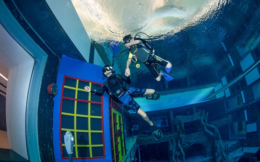 Scuba divers exploring underwater structures at Deep Dive Dubai.
