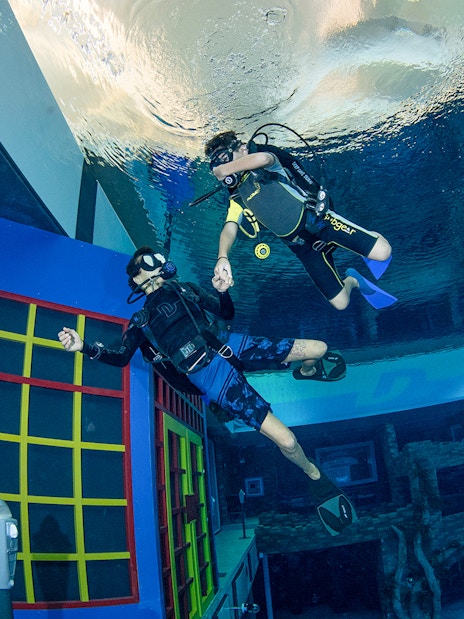 Scuba divers exploring underwater structures at Deep Dive Dubai.