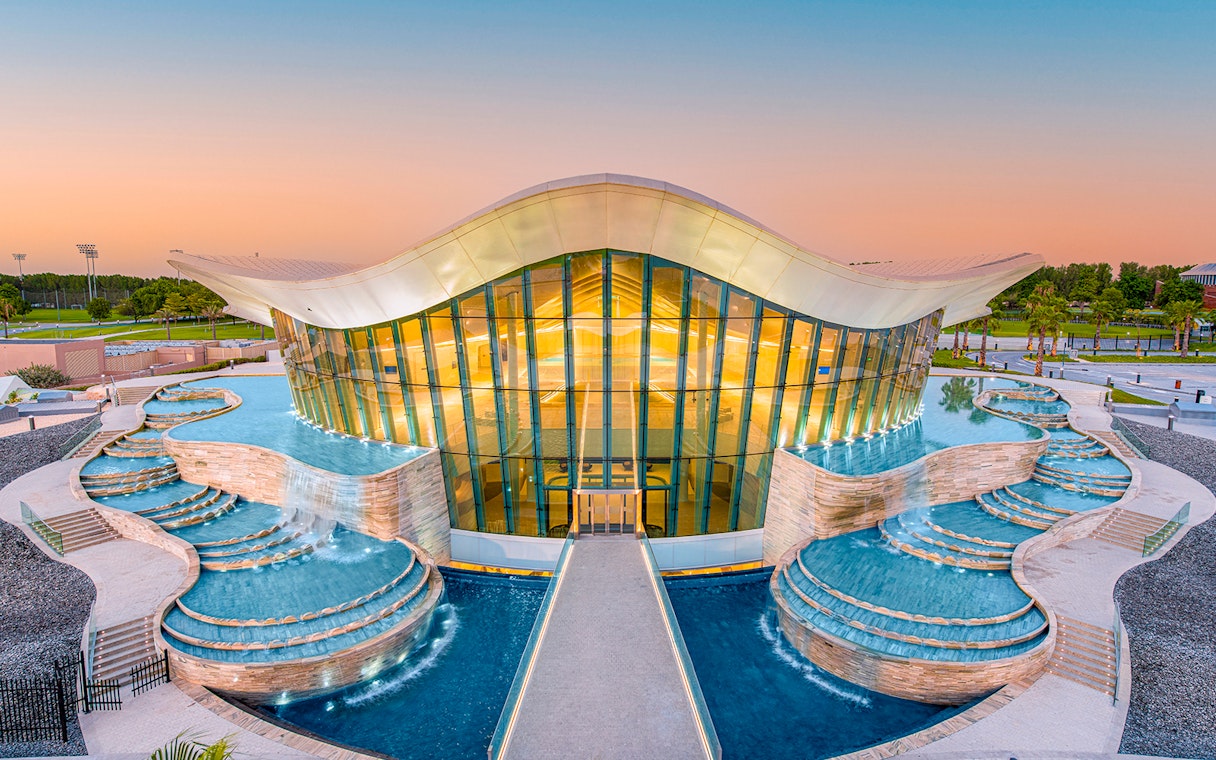 Deep Dive Dubai building with cascading pools at sunset.