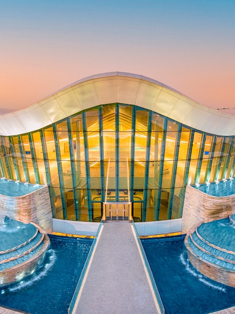 Deep Dive Dubai building with cascading pools at sunset.