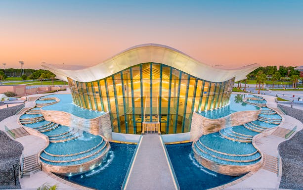 Deep Dive Dubai building with cascading pools at sunset.