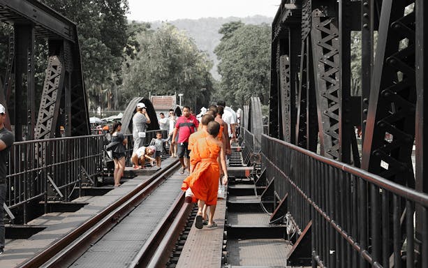 Visitors walking on the Bridge over the River Kwai during Erawan National Park tour.