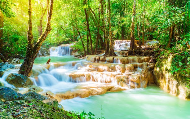 Erawan Waterfall cascading through lush forest in Erawan National Park, Thailand.