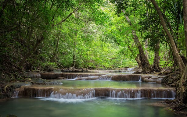 Erawan Waterfall tiers surrounded by lush forest in Erawan National Park, Thailand.