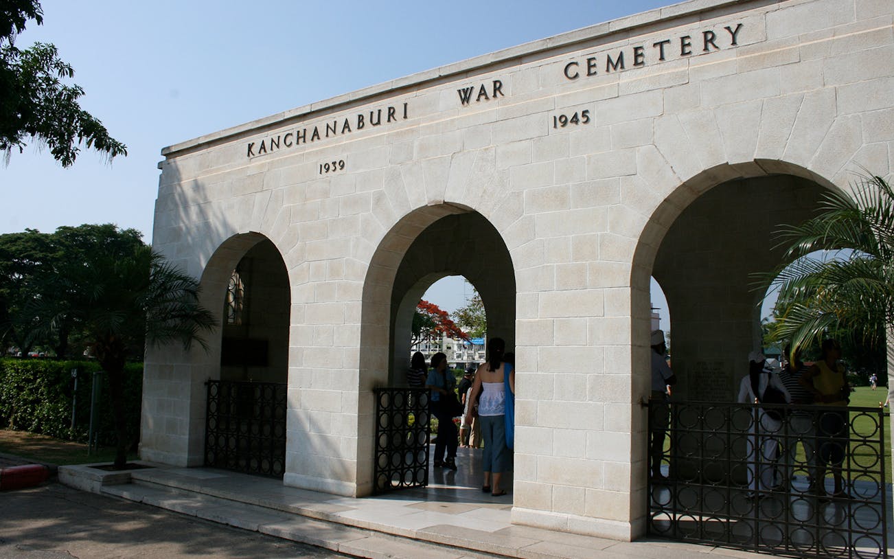 Kanchanaburi War Cemetery entrance with visitors, part of Erawan National Park Tour.