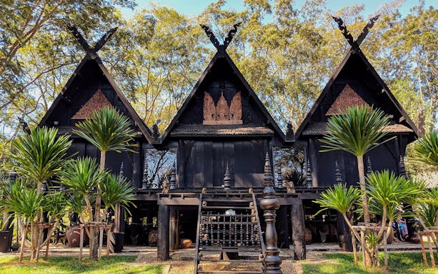 Black House museum with traditional architecture in Chiang Rai, surrounded by lush greenery.