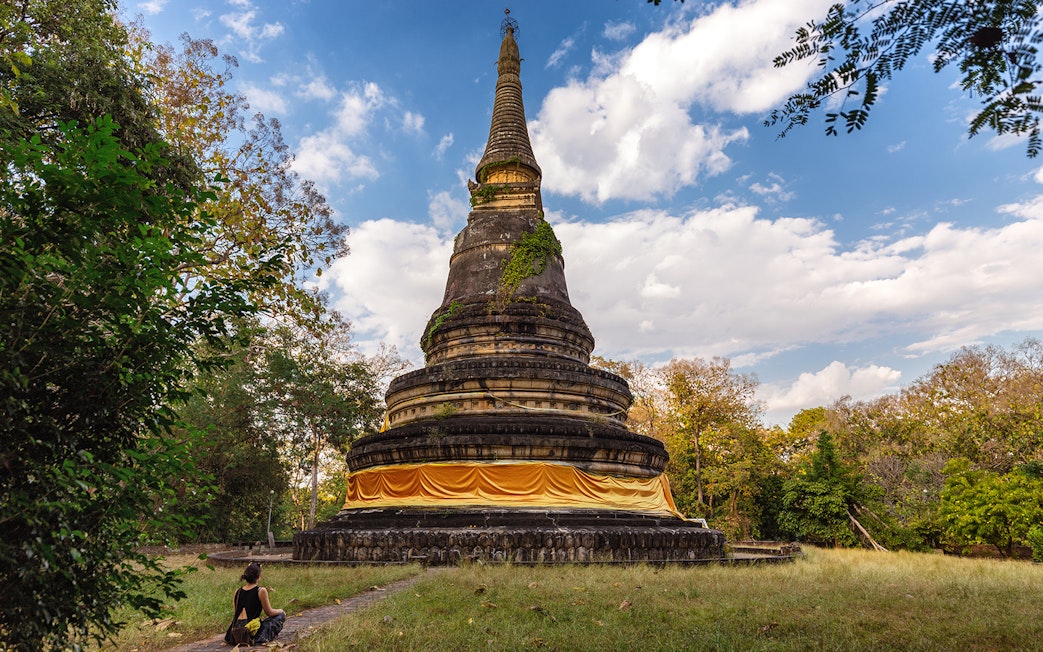 Ancient stupa at Wat Pha Lat surrounded by trees during sunrise on the Doi Suthep tour.