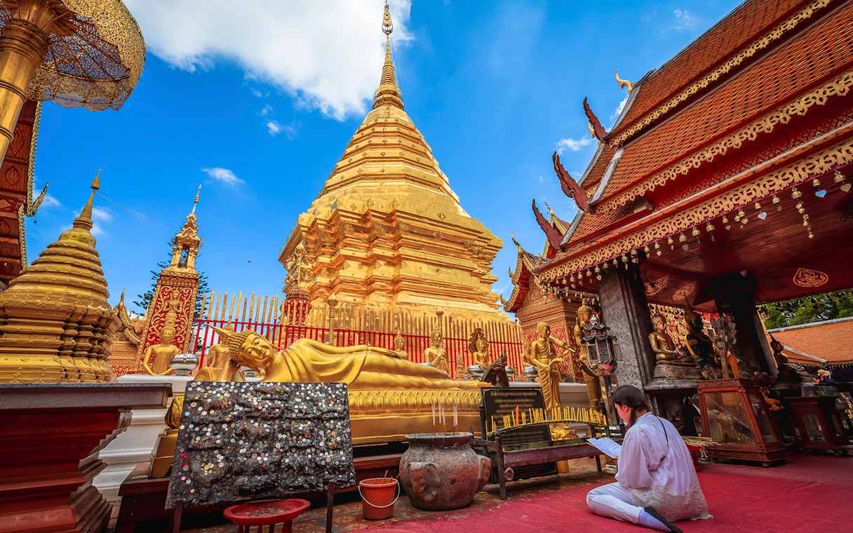 Golden pagoda and reclining Buddha at Wat Phra That Doi Suthep, Chiang Mai, during sunrise tour.