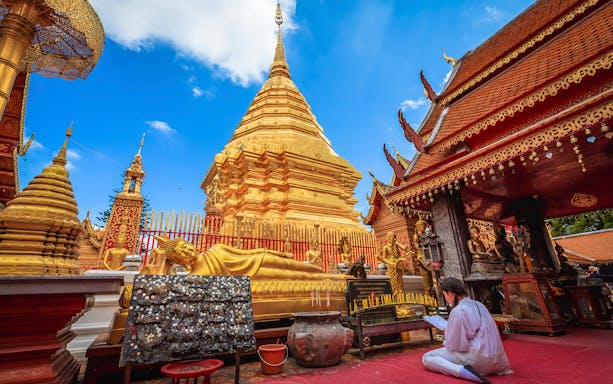 Golden pagoda and reclining Buddha at Wat Phra That Doi Suthep, Chiang Mai, during sunrise tour.