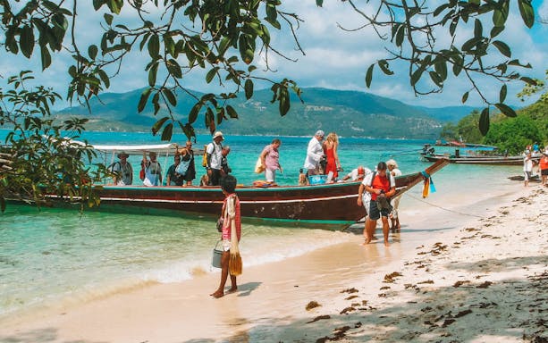 Tourists disembarking from a boat on a sandy beach during the Koh Samui Island Hopping Tour.