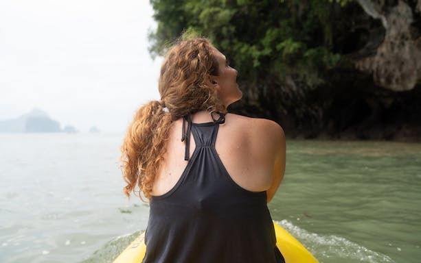 Person kayaking near lush cliffs on Koh Samui Island tour.